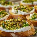 Goat cheese and pistachio bruschetta on a wooden tray with fresh thyme and pistachios.